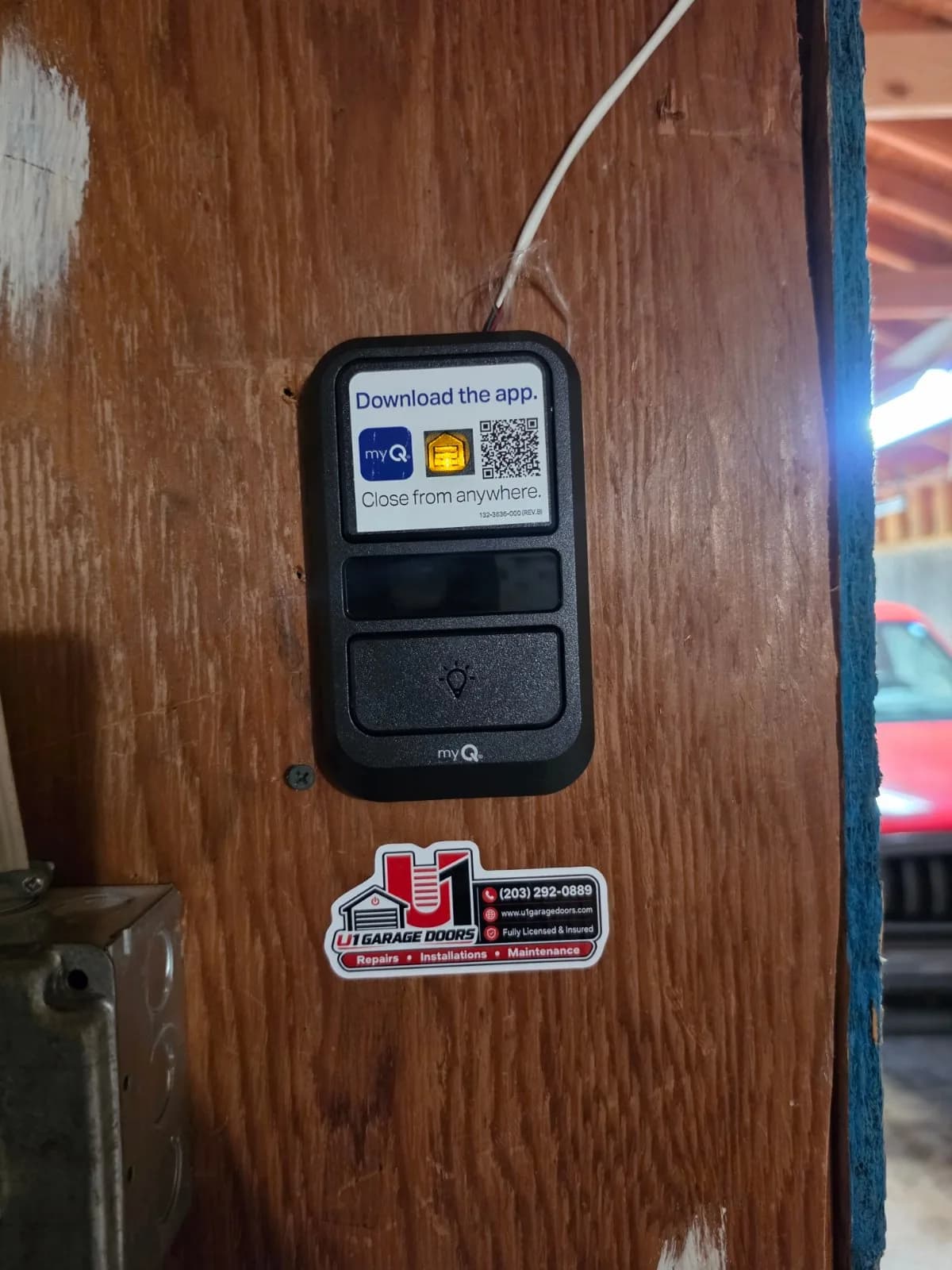 Black LiftMaster myQ wall control panel attached to wooden wall framing.